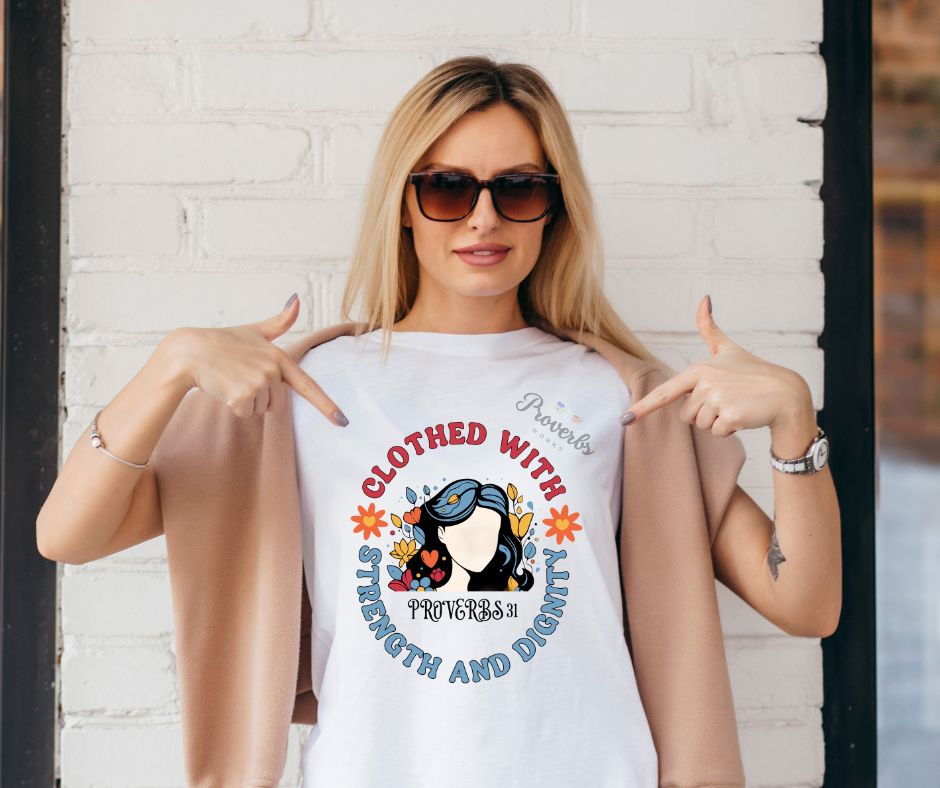 Woman wearing a white t-shirt with a graphic design and text, pointing to the shirt.